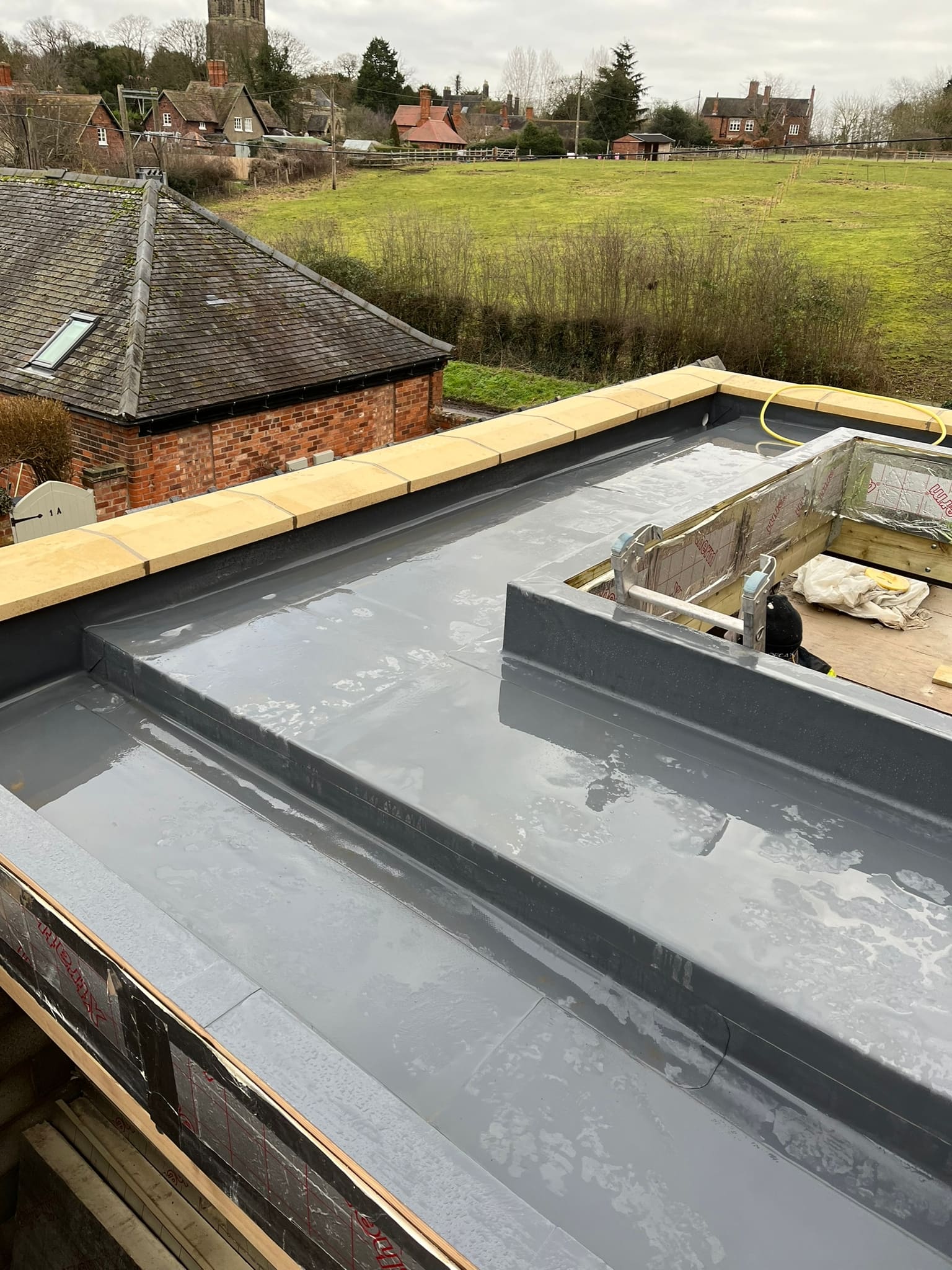 New brick extension shell with sandstone coping and a grey fibreglass flat roof